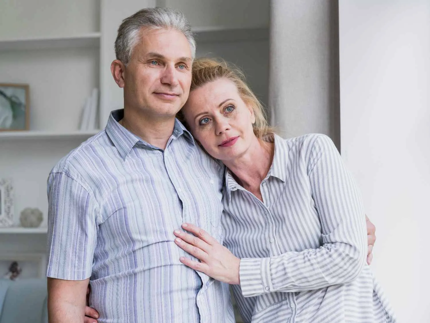 An older couple standing close together at home